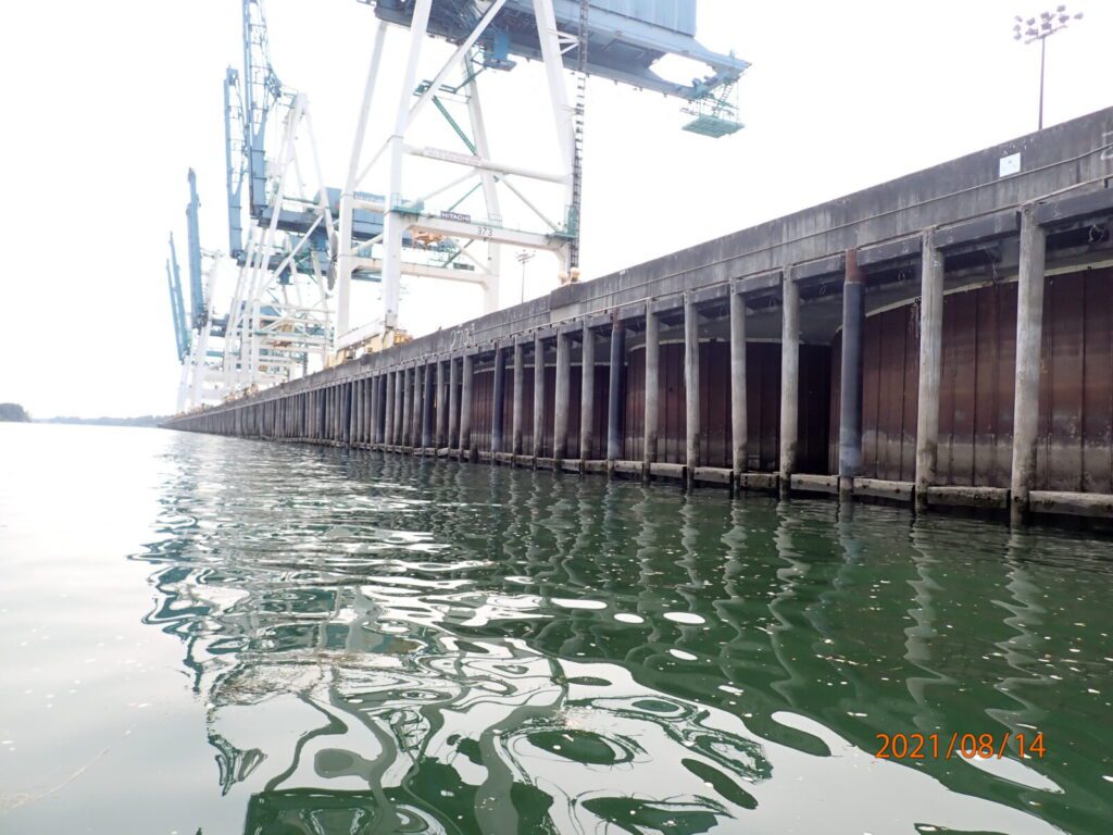 Large industrial cranes and a concrete pier extend over the water at a port facility. Photo taken on August 14, 2021.