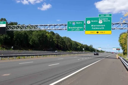 An empty multi-lane highway with green exit signs overhead for Interstate 95 North and Business Route 17 toward Warrenton and Falmouth under a blue sky with some clouds.